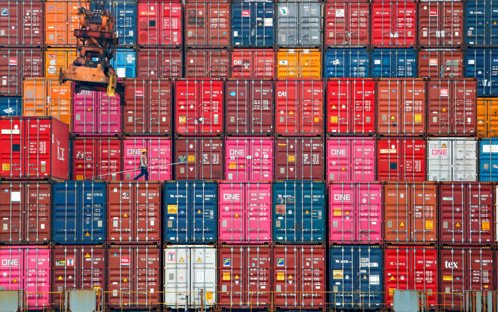 World Bank Forecast Economic Growth Logistics Impact file photo: a worker walks on stacks of containers at the tanjung priok port in jakarta